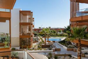 uitzicht op een binnenplaats met palmbomen en een zwembad bij Terraços do Rio in Portimão