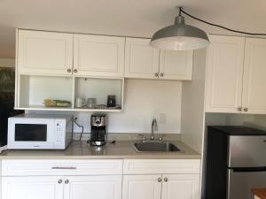 a kitchen with white cabinets and a microwave and a sink at one bedroom suite near Hillside mall in Victoria