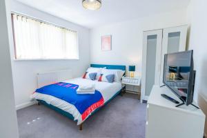 a bedroom with a bed and a flat screen tv at 4 en-suite bedroom house with free parking Aylesbury in Buckinghamshire
