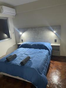 um quarto com uma cama azul com duas almofadas em Departamento menduca em Mendoza