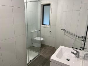 Baño blanco con aseo y lavamanos en BENDIGO BOTANIC MOTEL- with KING BEDS-REFURBISHED 2022, en Bendigo