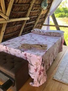 łóżko w krytym strzechą pokoju z różowym kocem w obiekcie JARDIM ENCANTADO ECOHOSPEDARIA w mieście Camaçari
