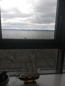 a model ship in a window with a view of the ocean at Stunning Waterfront Western harbour Apartment in Edinburgh