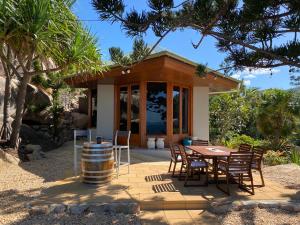 una casa y un patio con mesa y sillas en The Boulders - Oceanfront Couple's Retreat with private pool near ferry, en Nelly Bay