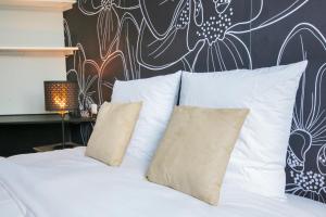 - un lit avec des oreillers blancs et un mur orné de fleurs dans l'établissement Le Vintage, T2 hypercentre chic et cosy, Wifi par SOVALFI, à Saint-Étienne