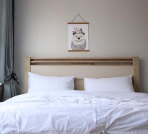 a bed with white sheets and a picture of a dog at Hongdae Residence-2 1min from Hongik Uni station Exit #1 in Seoul