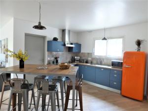 a kitchen with blue cabinets and an orange refrigerator at Detached holiday home with private garden in Carcans