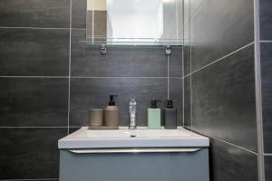 een badkamer met een witte wastafel en een spiegel bij L'Industriel, T2 hypercentre chic et cosy, Wifi par SOVALFI in Saint-Étienne