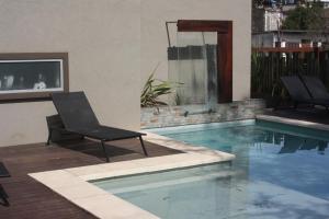 a swimming pool with two chairs next to a house at Complejo de las Artes in Pinamar