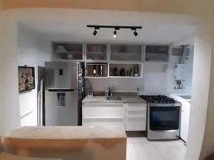 una cocina con electrodomésticos de acero inoxidable y armarios blancos en Apartamento Padrão em condominio completo no Recreio, en Río de Janeiro