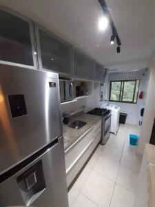 uma cozinha com um frigorífico e electrodomésticos em aço inoxidável em Apartamento Padrão em condominio completo no Recreio no Rio de Janeiro