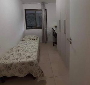 um pequeno quarto com uma cama e uma janela em Apartamento Padrão em condominio completo no Recreio no Rio de Janeiro