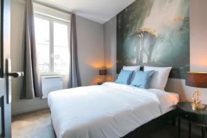 - une chambre avec un grand lit blanc orné d'une peinture murale dans l'établissement L'Eléphant, T2 hypercentre chic et cosy, Wifi par SOVALFI, à Saint-Étienne