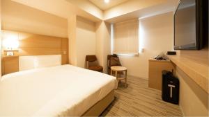 a hotel room with a white bed and a desk at Via Inn Higashiginza in Tokyo