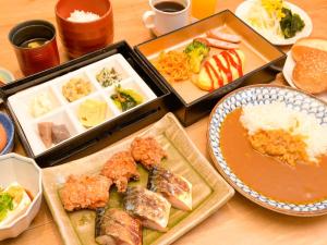une table recouverte de plateaux de différents types de nourriture dans l'établissement Via Inn Shin Osaka West, à Osaka