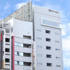 wysoki biały budynek z napisem w obiekcie Via Inn Umeda w Osace