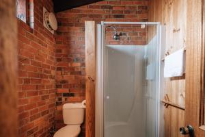 a brick bathroom with a shower and a toilet at Diamond House Heritage Restaurant and Motor Inn in Stawell