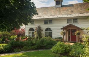 a white house with a red door and a yard at Lang House on Main Street Bed & Breakfast in Burlington