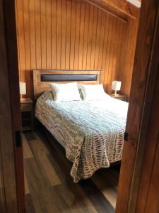 Schlafzimmer mit einem Bett mit Holzwänden und Holzböden in der Unterkunft Snowko in Malalcahuello