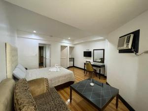 ein Hotelzimmer mit einem Bett und einem Sofa in der Unterkunft Town and Country Hotel V Mapa in Manila