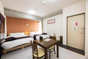 1 dormitorio con 2 camas, mesa y escritorio en STAYTUS en Kagoshima