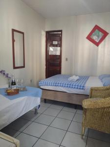 a bedroom with two beds and a chair and a mirror at Pousada Centro e Praia in Fortaleza