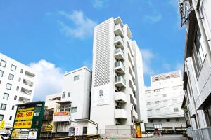 a tall white building in the middle of a city at STAYTUS in Kagoshima