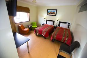 una habitación de hotel con 2 camas y una silla en Hotel Tinkus Inn, en Lima