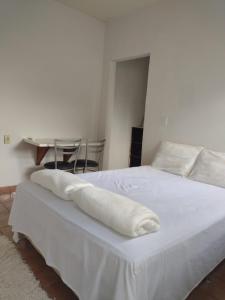 um quarto com uma cama branca com duas toalhas em Pousada Recanto Alaketu Hospedagens em Campo Grande