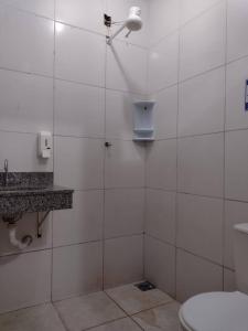 uma casa de banho em azulejos brancos com um WC e um chuveiro em Pousada Recanto Alaketu Hospedagens em Campo Grande