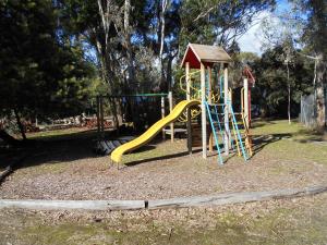 a child's playground with a wooden park bench at Grampians View Cottages and Units in Halls Gap