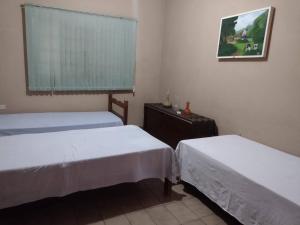 a room with two beds and a window in it at Pousada Recanto Alaketu Hospedagens in Campo Grande