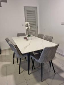a white table with chairs and a vase with flowers at Modern 4BR Double Storey @ Setia Alam in Shah Alam