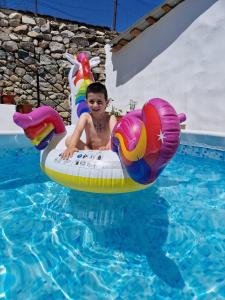a young boy is riding on an inflatable swimmer in a pool at Casa Adelin in Eşelniţa