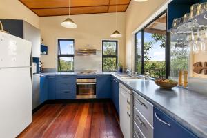 una cocina con armarios azules y una gran ventana en COASTING - Straddie Style Beach House en Point Lookout