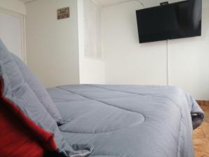 a bed with white sheets and a flat screen tv at Habitación Privada Cerca al Aeropuerto y Terminal in Bogotá