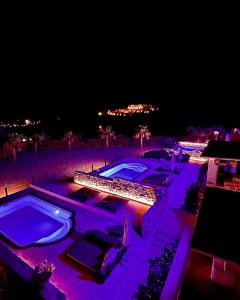a resort with two swimming pools at night at Aurora Mykonos Villas in Kalafatis