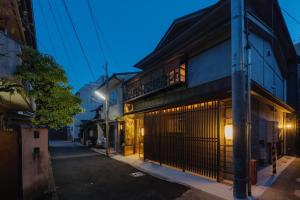 um edifício com uma varanda numa rua à noite em THE MACHIYA KAZAHAYA em Quioto