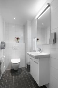 a white bathroom with a toilet and a sink at Hotel Copenhagen Apartments in Copenhagen