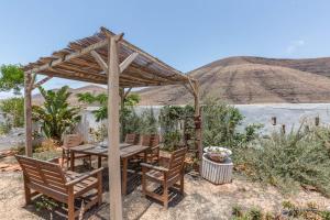 una mesa de madera y sillas bajo una pérgola en Kikiki House Vista Jardín La 5 en Vallebrón