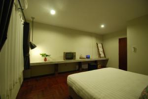 a room with a bed and a desk with a tv at Pak Ping The Cozy Living in Chiangmai in Chiang Mai