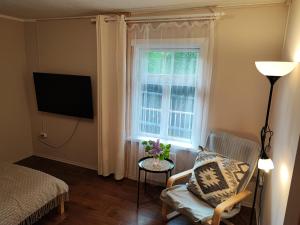 a living room with a chair and a window at Piejūras Namiņš in Ragaciems