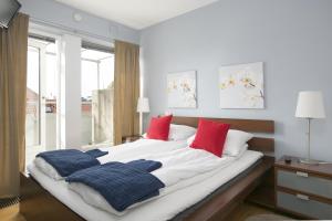 a bedroom with a large bed with red and blue pillows at Hotel Copenhagen Apartments in Copenhagen