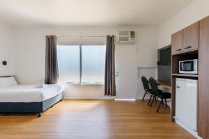 a bedroom with a bed and a kitchen with a microwave at Boomerang Hotel in Mackay