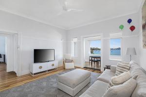 Una sala de estar con un sofá y un televisor de pantalla plana. en Harbour View in Rose Bay, en Sídney
