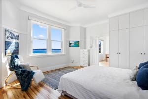 Un dormitorio blanco con una cama y una silla. en Harbour View in Rose Bay, en Sídney