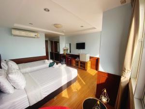 a hotel room with two beds and a television at Navanakorn Golden View in Ban Lam Rua Taek