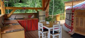 a kitchen and a table on a deck with a tent at Yourte indépendante en pleine nature, proche d'Ajaccio in Carbuccia