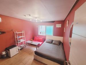 ソウルにあるOlive hostel Wの赤い壁のベッドルーム1室、ベッド1台、棚が備わります。