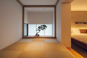 a bedroom with a bed and a window with a tree at nol kyoto sanjo in Kyoto